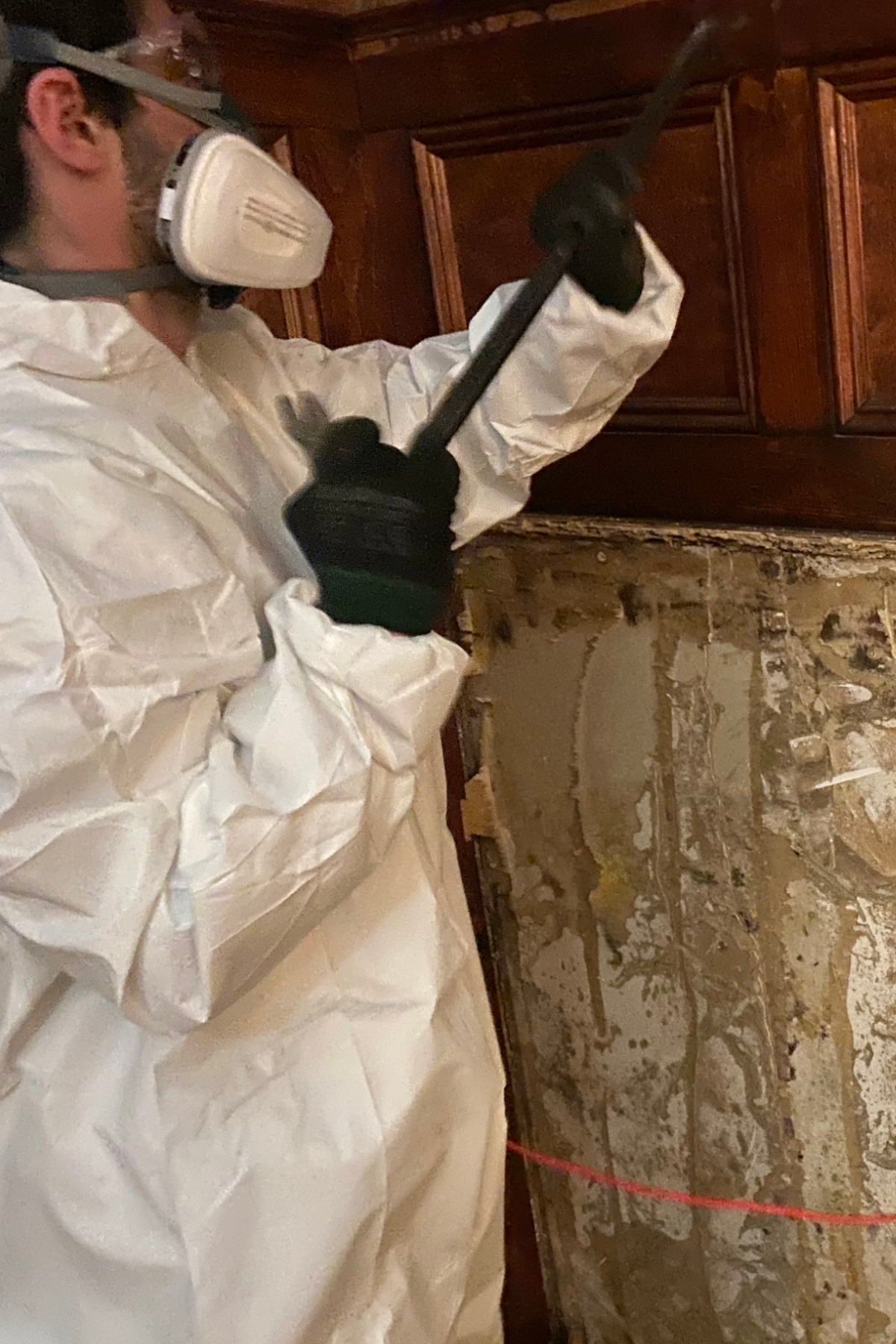 Worker wearing PPE equipment cleaning mold from a wall